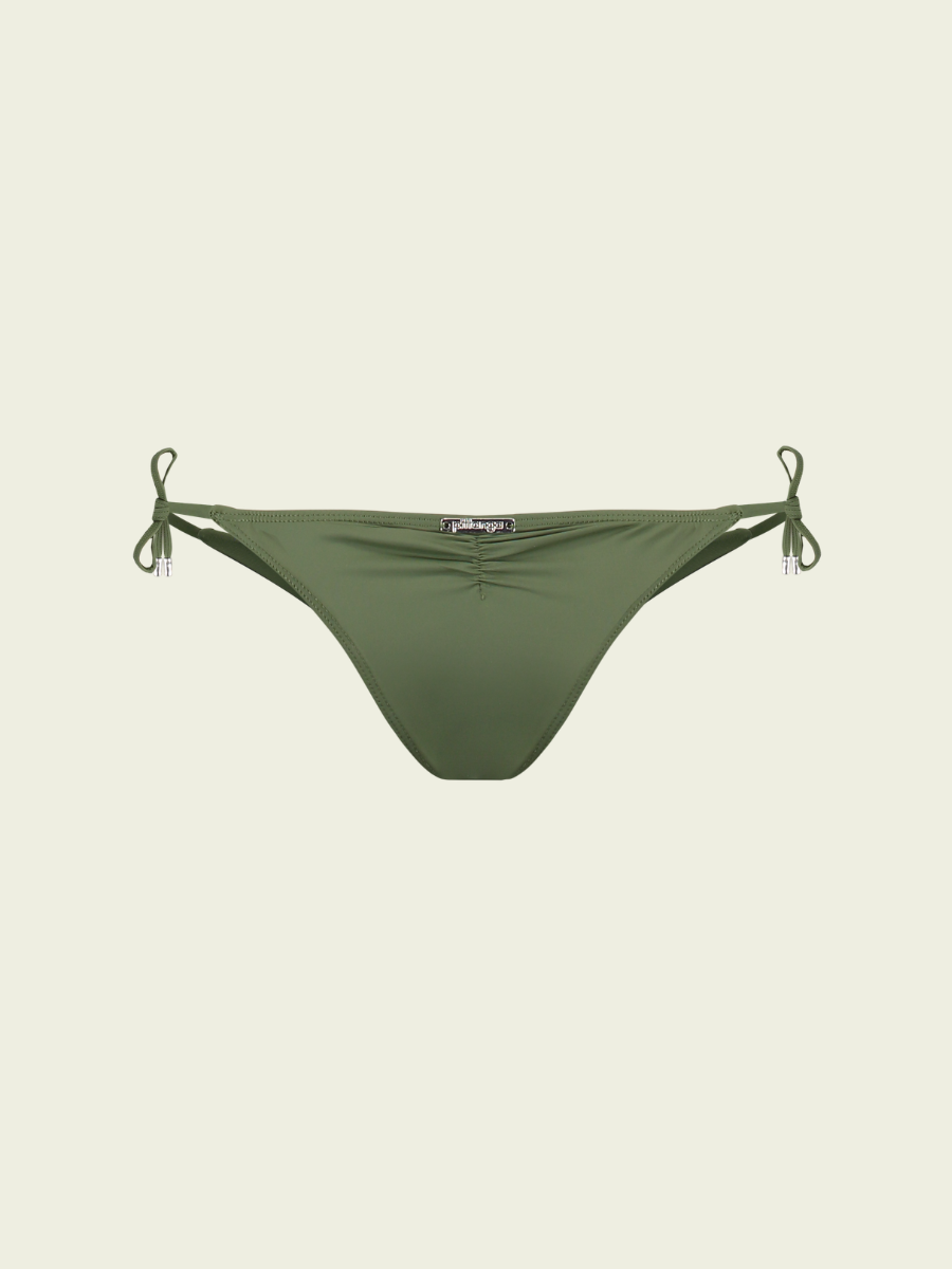 Green bikini bottom with string ties on a light beige background